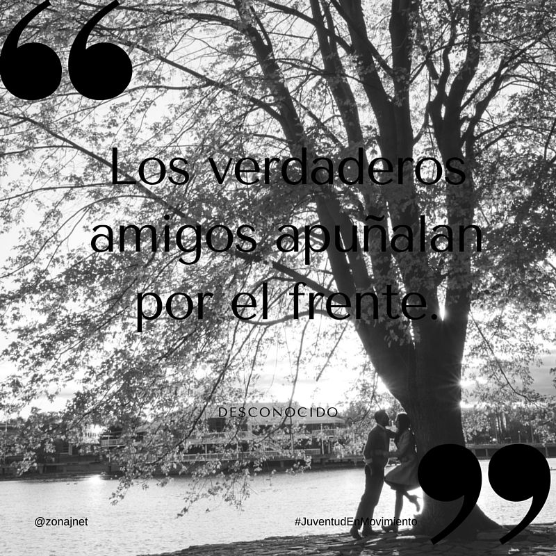 Una pareja debajo de un árbol al lado de un río con unas casas al fondo