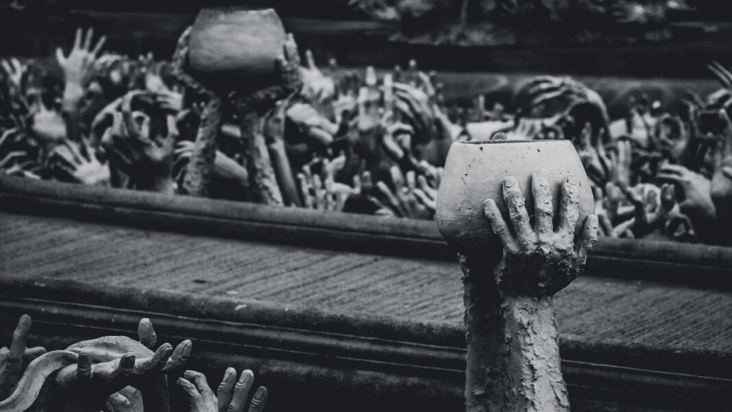 Escultura en blanco y negro con numerosos brazos y manos alzados; varias manos sostienen recipientes de barro, con una mano en primer plano sobre una cornisa.