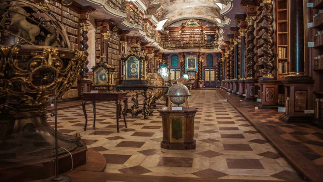 Interior de una biblioteca histórica con estanterías de madera, globos antiguos, suelo ajedrezado y techo decorado con pinturas.