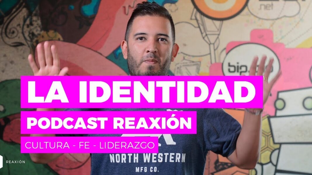 Hombre de barba con camiseta azul y manos levantadas frente a un mural colorido con letras grandes que dicen La Identidad, Podcast Reacción, Cultura, Fe y Liderazgo.
