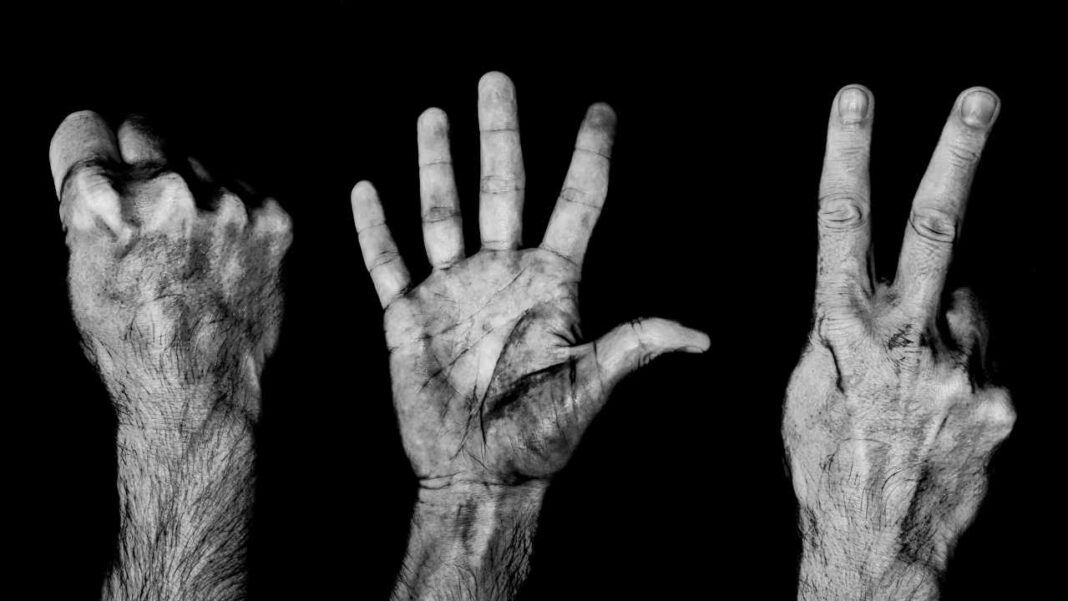 Fotografía en blanco y negro de tres manos y antebrazos sobre fondo negro: un puño cerrado, una palma abierta y una mano con dos dedos levantados.