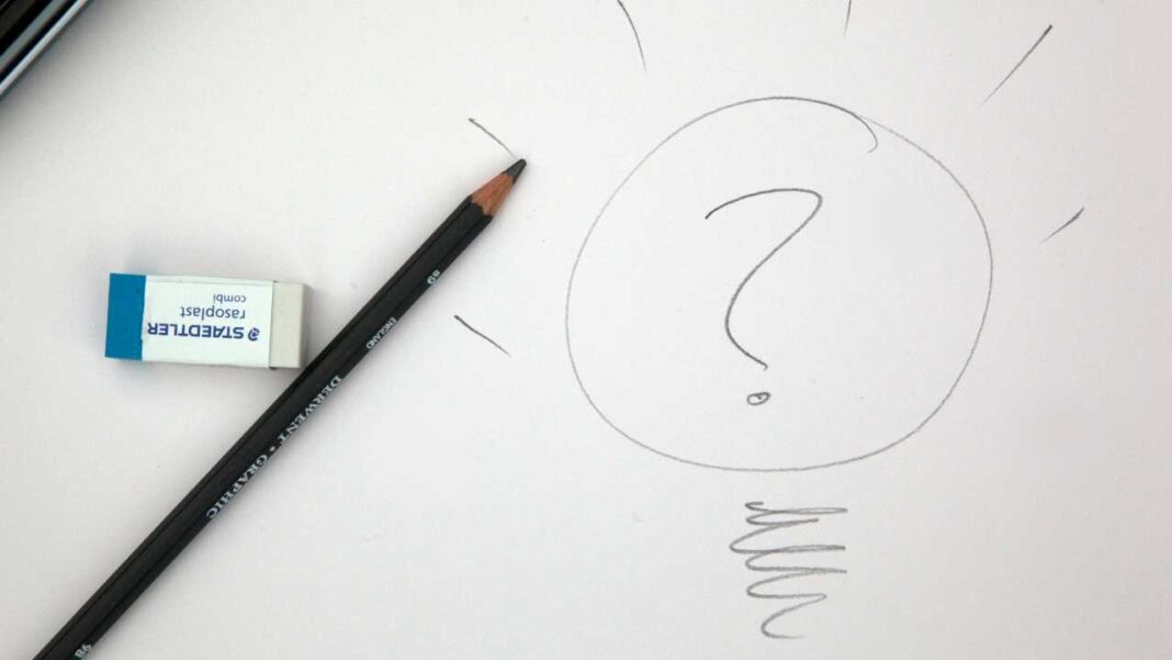Sobre papel blanco, un lápiz negro y una goma de borrar con texto visible junto a un signo de interrogación dibujado dentro de un círculo.