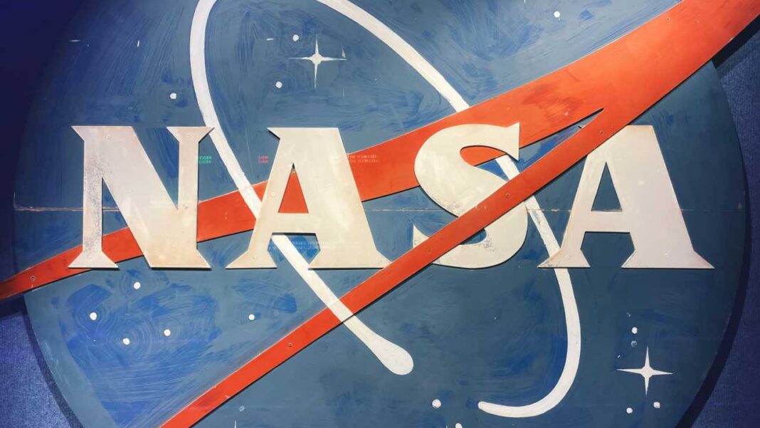 Letras grandes de NASA en blanco sobre un fondo azul con una franja roja diagonal, una línea orbital blanca y pequeñas estrellas.